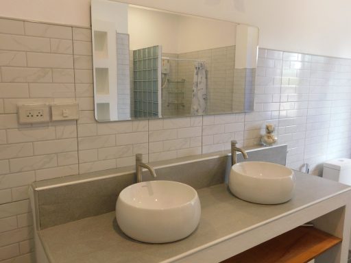 Modern bathroom with two white vessel sinks and a large mirror above them.