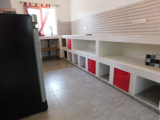 Modern kitchen with white shelves, red accent storage, and a refrigerator.