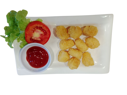 Plate of golden chicken nuggets with a side of ketchup and a tomato slice, garnished with lettuce.
