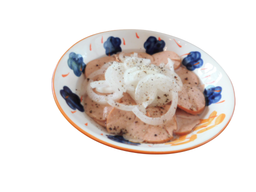 Plate of sliced meat topped with onions, garnished with black pepper.