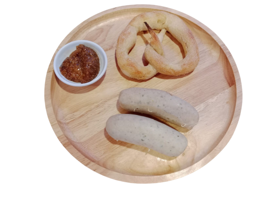 A wooden platter with pretzels and two sweet dumplings served with a bowl of dip.